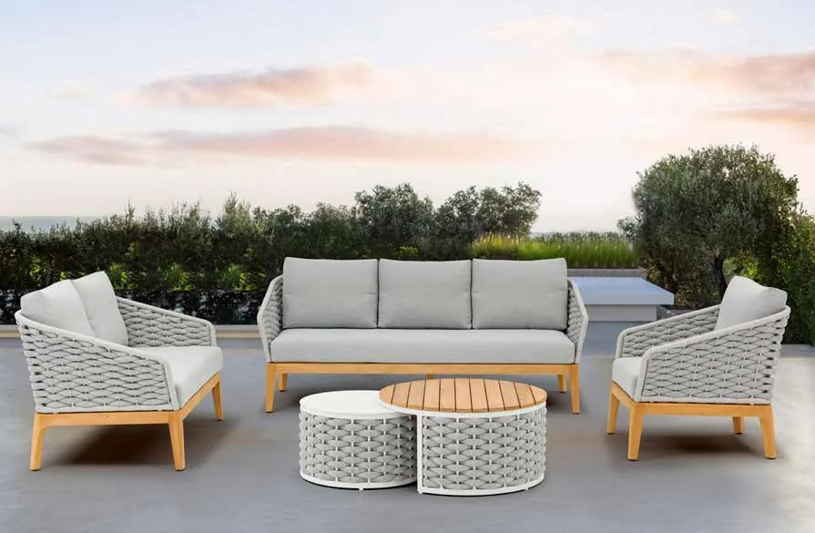 A light woven outdoor sofa set with pale cushions and timber-coloured frame details.