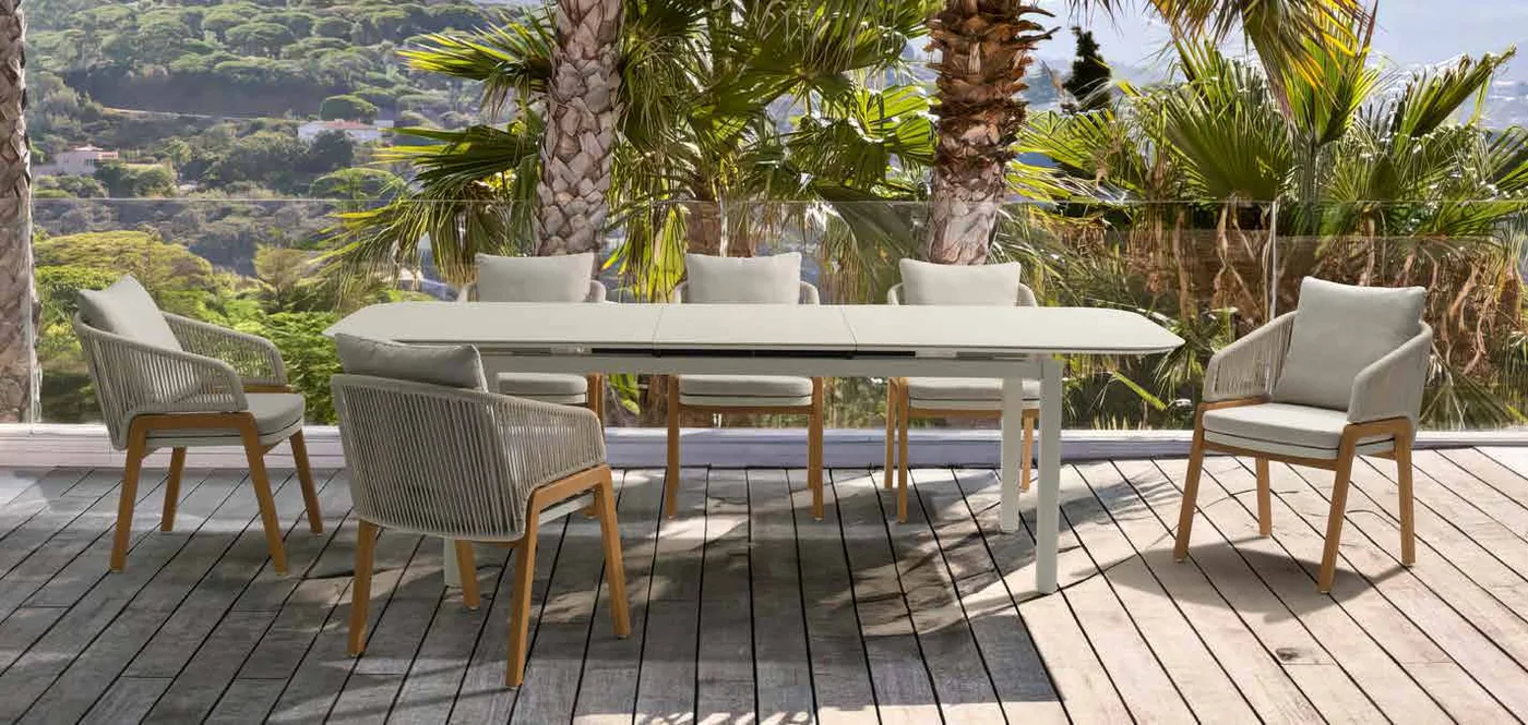 A contemporary outdoor dining table surrounded by dark-framed patio chairs.