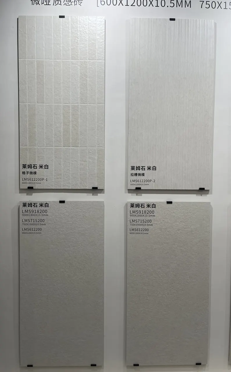 Four pale limestone-look surface boards on a showroom display, showing smooth and patterned finishes.