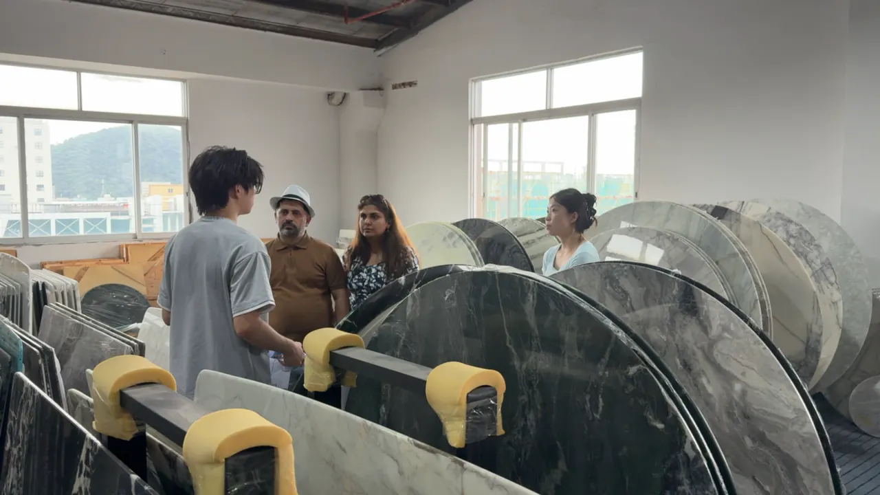 People examine large stone slabs together at a material showroom.